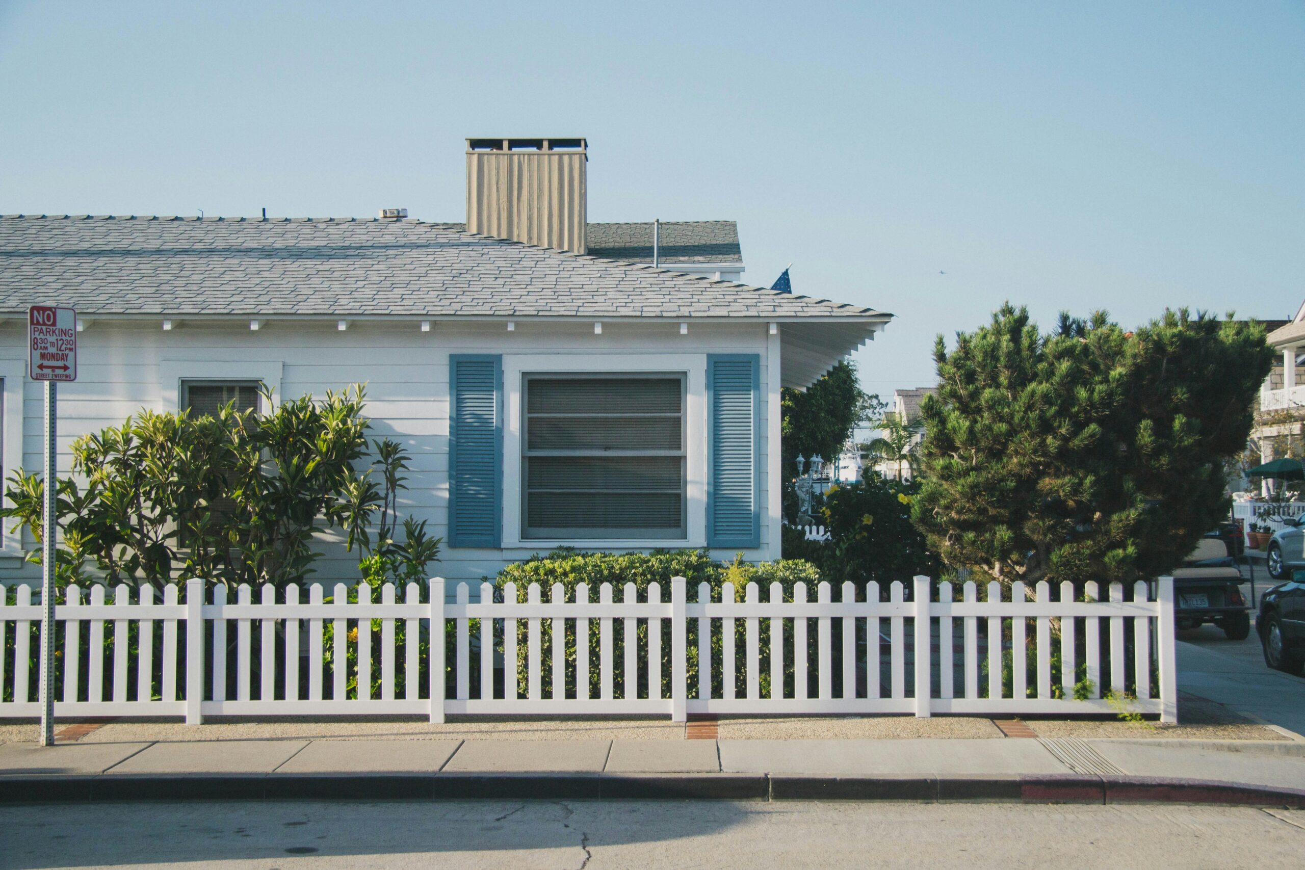 A beach house that sits on a street corner with a white picket fence.